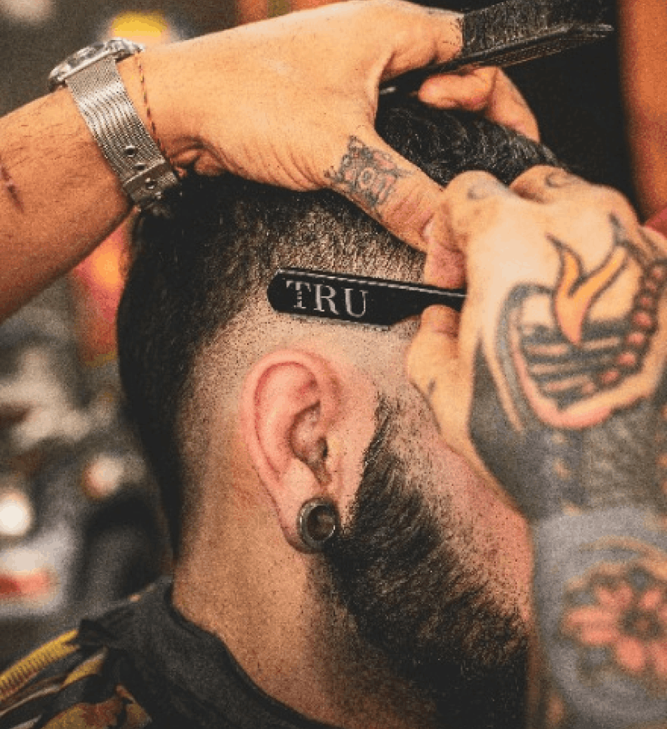 Barbero perfilando el corte de un cliente en su barbería